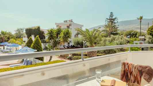 Altan med bord, bog og glas; udsigt over have og bygninger. (AI-genereret tekst)