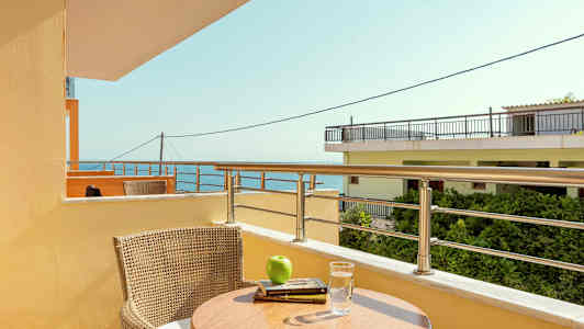 En altan med udsigt over havet, med et bord og en stol. (AI-genereret tekst)