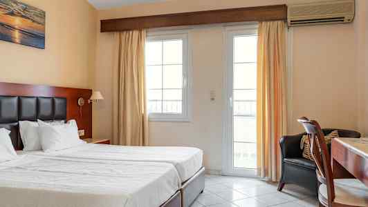 Hotelværelse med to enkeltsenge, skrivebord og vindue med lyse gardiner. (AI-genereret tekst)