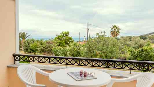 Altan med udsigt over træer og hav, med bord og stole. (AI-genereret tekst)