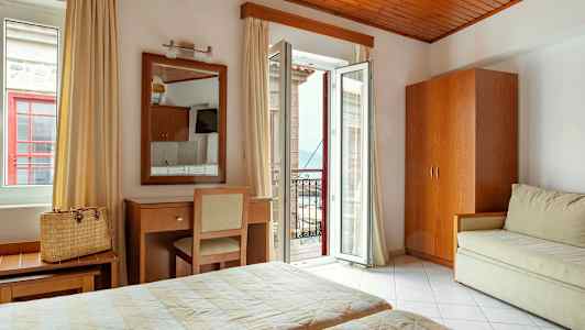 Et hotelværelse med to senge, et spejl over et skrivebord og en stol samt en åben altandør med udsigt. (AI-genereret tekst)