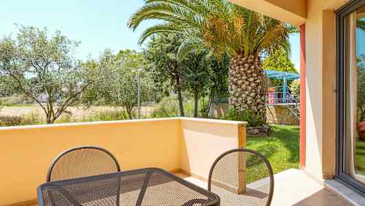 Altan med bord og stole samt udsigt over en have med palmer. (AI-genereret tekst)