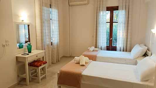 Et hotelværelse med to enkeltsenge, et skrivebord og et spejl. (AI-genereret tekst)