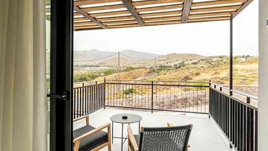 Altan med to stole og et bord med udsigt til et landskab. (AI-genereret tekst)