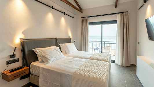 Et hotelværelse med to enkeltsenge og en altan med havudsigt. (AI-genereret tekst)