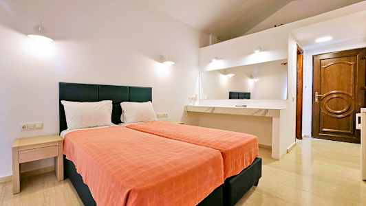 Hotelværelse med to enkeltsenge, et skrivebord med spejl og hvide vægge. (AI-genereret tekst)