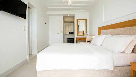 Moderne hotelværelse med en bred seng, hvidt interiør og trædetaljer. (AI-genereret tekst)