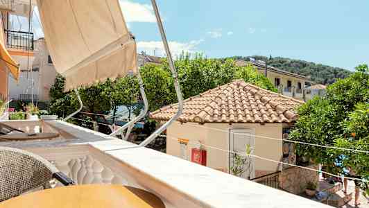 Udsigt over en solrig terrasse med tag og træer i baggrunden. (AI-genereret tekst)