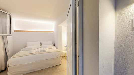 Et lyst soveværelsesinteriør med en opredt dobbeltseng. (AI-genereret tekst)