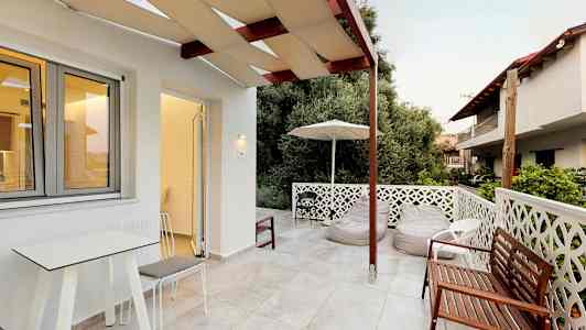 En terrasse med udendørs møbler og udsigt til beplantning. (AI-genereret tekst)