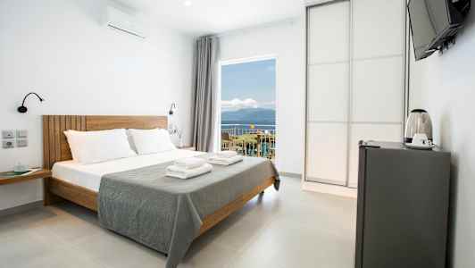 Moderne hotelværelse med dobbeltseng, minikøleskab og havudsigt. (AI-genereret tekst)