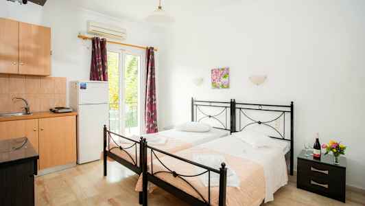 To enkeltsenge med lyserøde tæpper i et værelse med køkkenudstyr. (AI-genereret tekst)