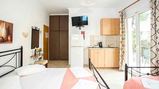 Et lyst og luftigt soveværelse med dobbeltsenge, en lille køkkenafdeling og adgang til en altan. (AI-genereret tekst)