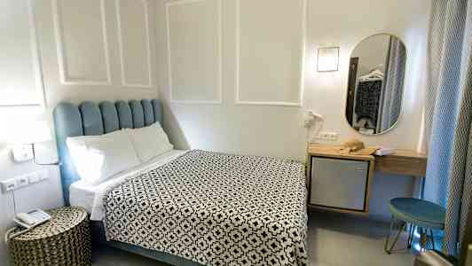 Et hotelværelse med en seng, et natbord og et spejl. (AI-genereret tekst)