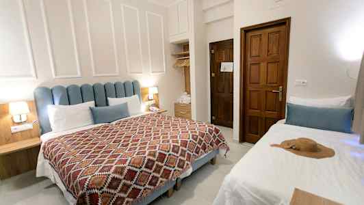 Et hotelværelse med en dobbeltseng, en enkeltseng og træinteriør. (AI-genereret tekst)