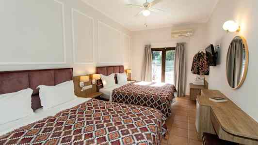 Hotelværelse med to senge og et skrivebord, dekoreret med geometriske mønstrede sengetæpper. (AI-genereret tekst)