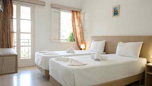 Et hotelværelse med to senge, hvidt sengetøj og vinduer med gardiner. (AI-genereret tekst)