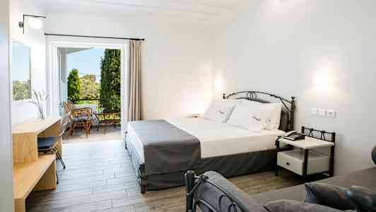 Moderne hotelværelse med seng, skrivebord og adgang til møbleret altan. (AI-genereret tekst)