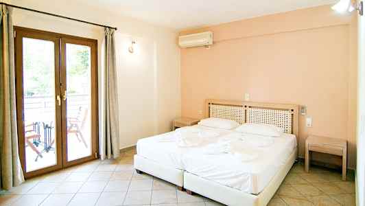 Et hotelværelse med en dobbeltseng, to natborde og en dør til en balkon. (AI-genereret tekst)