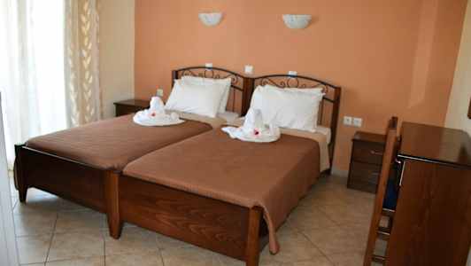 To enkeltsenge med hvidt sengetøj og dekoration, placeret i et rum med terrakotta vægfarve og mørke træmøbler. (AI-genereret tekst)