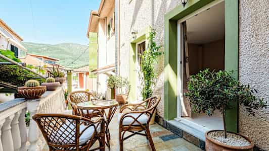 Terrasse med kurvemøbler, planter og udsigt til frodige bjerge. (AI-genereret tekst)