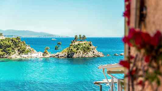 En lille ø med træer og et hus omgivet af blåt vand. (AI-genereret tekst)