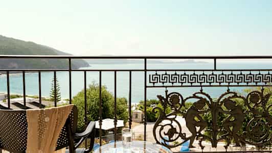 Udsigt fra en balkon med dekorativt rækværk over havet og kysten. (AI-genereret tekst)