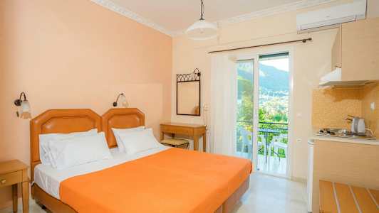 Hotelværelse med en orange seng, skrivebord og balkon med udsigt. (AI-genereret tekst)