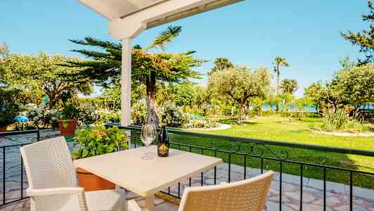 Udendørs servering med bord og stole foran en frodig have. (AI-genereret tekst)