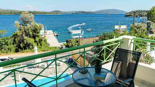 Udsigt fra en balkon over en blå bugt med både og frodige omgivelser. (AI-genereret tekst)