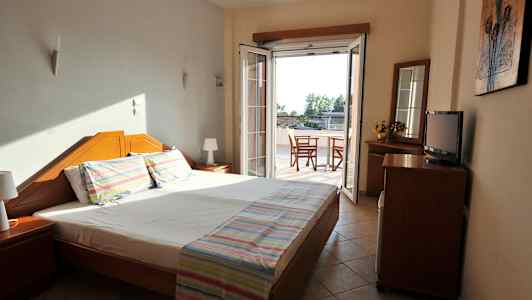 Et hotelværelse med en dobbeltseng og en dør til en balkon. (AI-genereret tekst)