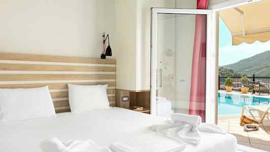 Et hotelværelse med en dobbeltseng og udsigt til en pool gennem en glasdør. (AI-genereret tekst)