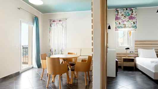 Moderne indrettet hotelværelse med spisebord, siddepladser og seng. (AI-genereret tekst)