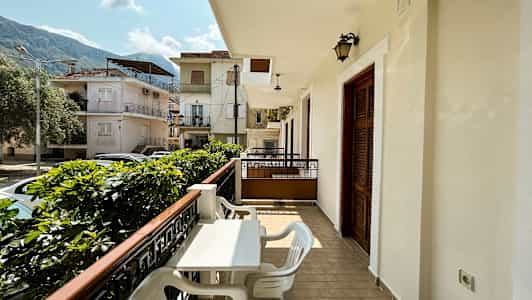 Altan med bord og stole og udsigt mod et boligområde med huse. (AI-genereret tekst)