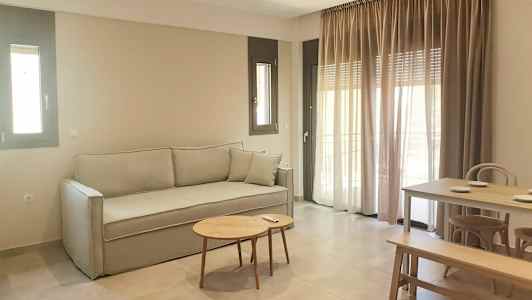 En siddegruppe med sofa, bord og spisebord. Vinduer med gardiner i baggrunden. (AI-genereret tekst)