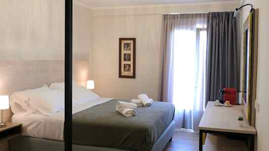 Moderne indrettet soveværelse med dobbeltseng, natbord og en skrivebordsflade med kaffemaskine. (AI-genereret tekst)