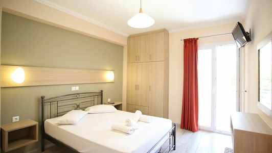 Et lyst hotelværelse med en seng, et skab og en altandør. (AI-genereret tekst)