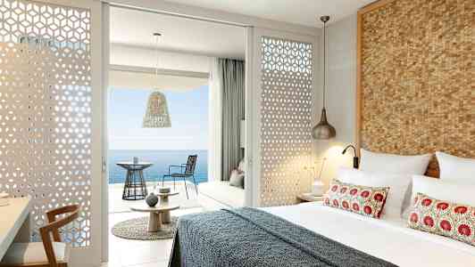 Moderne indrettet hotelværelse med udsigt over havet fra en møbleret balkon. (AI-genereret tekst)