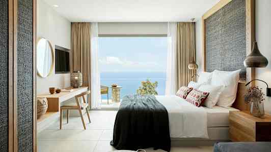 Moderne indrettet hotelværelse med havudsigt fra en stor glasdør. (AI-genereret tekst)