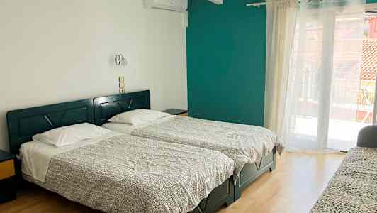 Et hotelværelse med to enkeltsenge, en sofa og en altandør. (AI-genereret tekst)