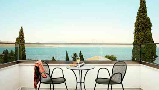 To stole og et bord på en terrasse med udsigt over havet. (AI-genereret tekst)