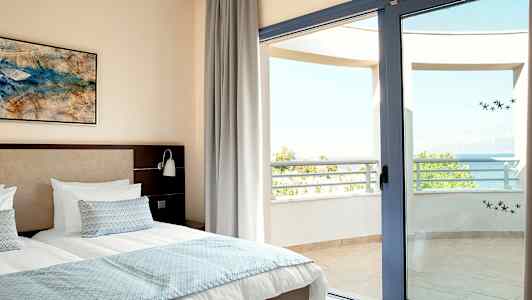 Billede af et soveværelse med dobbeltseng og en åben altandør mod havudsigt. (AI-genereret tekst)