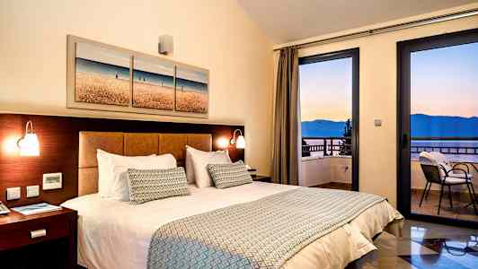 Værelse med dobbeltseng, natbord og havudsigt gennem vinduet. (AI-genereret tekst)