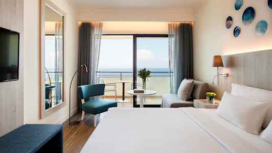 Hotelværelse med havudsigt, sofa, siddeområde og seng. (AI-genereret tekst)