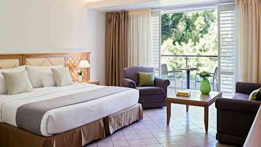 Interiør af hotelværelse med dobbeltseng, siddeområde og altan. (AI-genereret tekst)