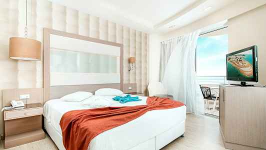 Hotelværelse med stor seng og udsigt til altan. (AI-genereret tekst)