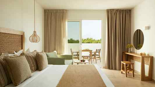 Et hotelværelse med en dobbeltseng, en siddegruppe, et skrivebord og adgang til en altan. (AI-genereret tekst)