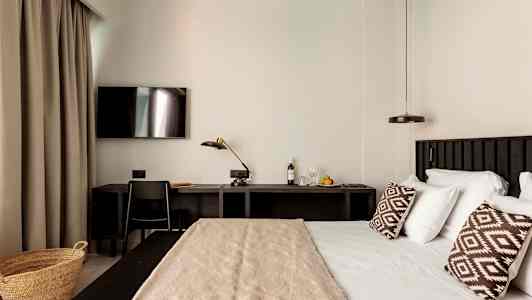 Et hotelværelse med en seng, skrivebord og TV. (AI-genereret tekst)