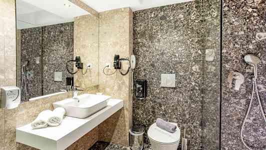 Et badeværelse med et spejl, håndvask, toilet og bruser. (AI-genereret tekst)