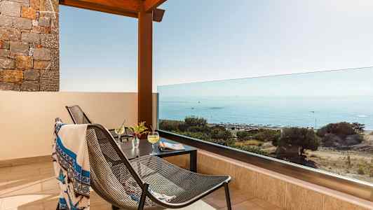 Terrasse med udsigt over havet, møbler og drikke på bordet. (AI-genereret tekst)